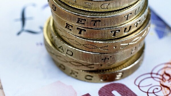 Seven pound coins on top of a ten pound note.